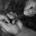 Zwart-wit afbeelding van twee handen die een touw vasthouden